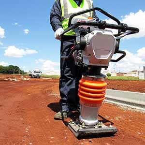 Operador de construção civil utilizando um equipamento de Compactar Terra