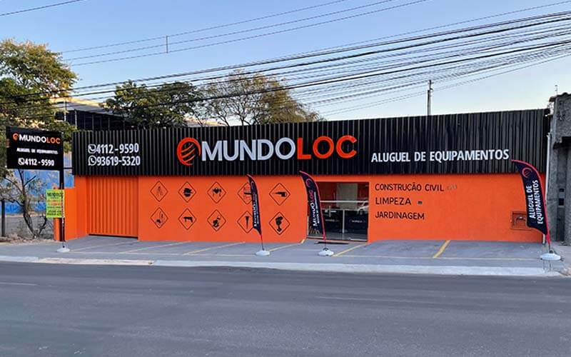 Loja MundoLoc com muro alaranjado e placa da fachada em preto e letreiro branco e alaranjado.